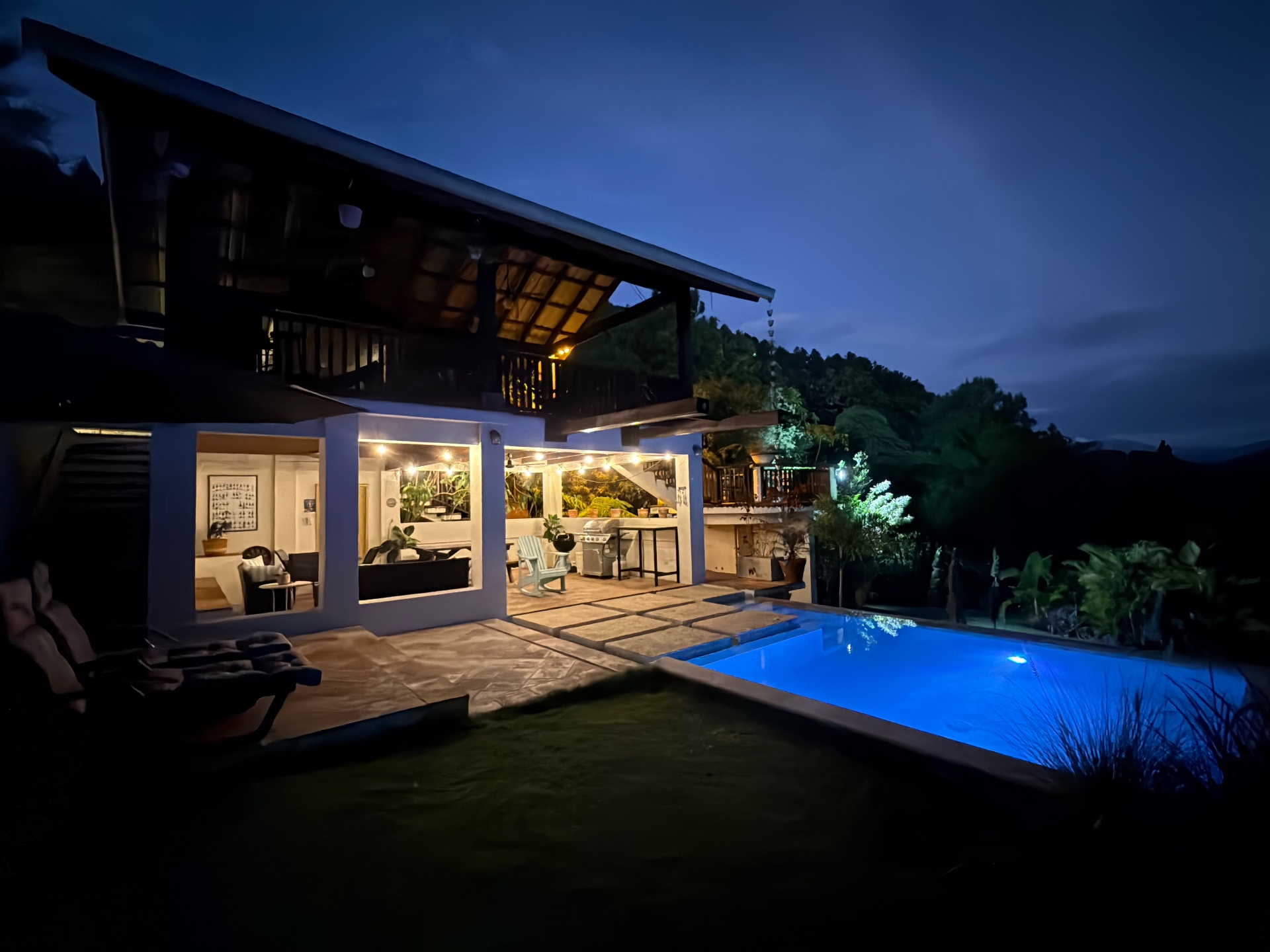 Villa del Pino iluminada de noche con la piscina brillante bajo el cielo de montaña
